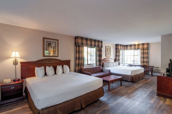 A hotel room with two beds, a sofa, a desk, a lamp, and a television. - Studio City Court Yard Hotel (Studio City)
