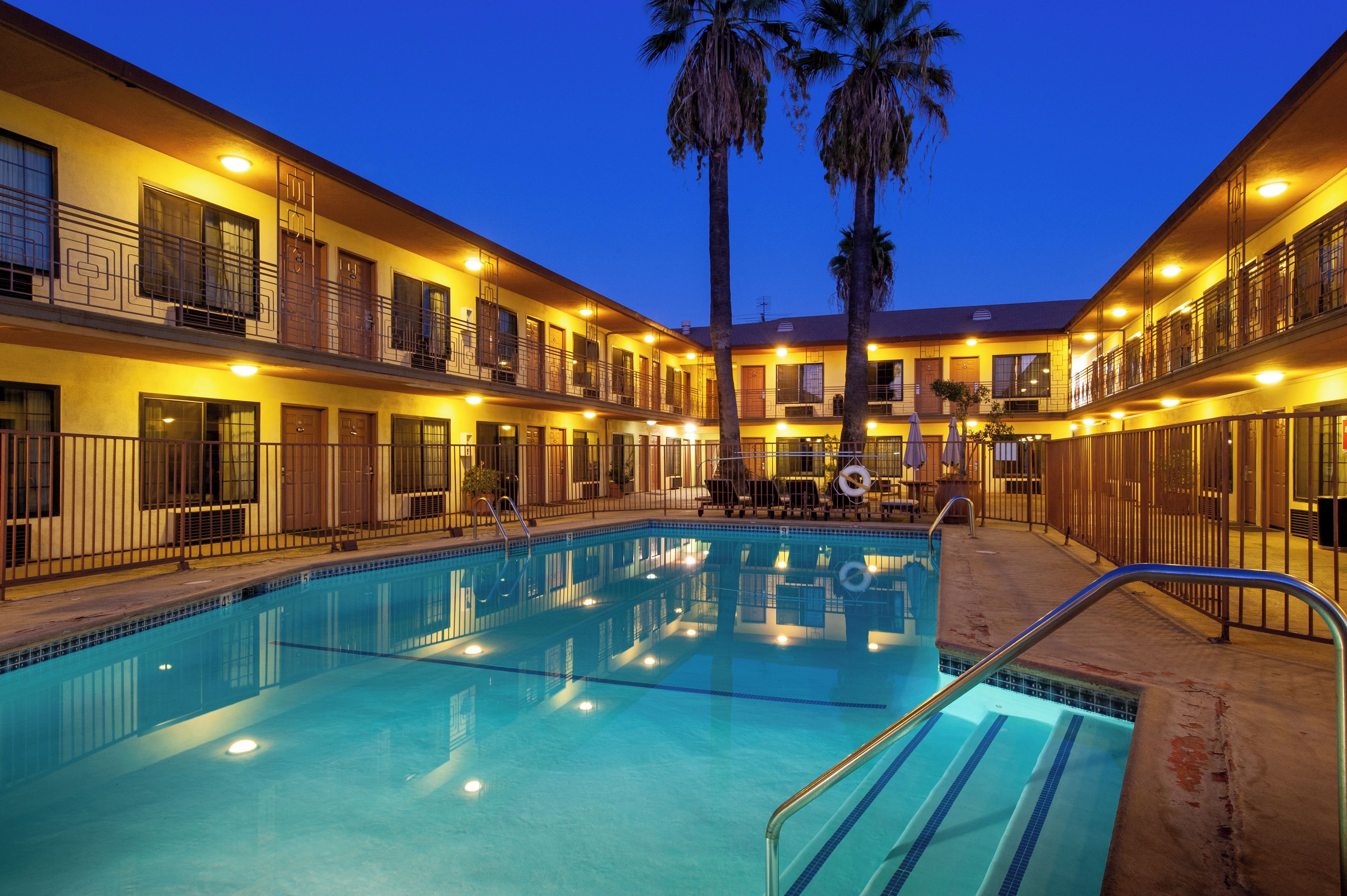 Un hôtel doté d’une piscine, de plusieurs balcons et de palmiers.