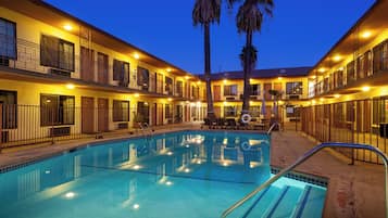 Un hôtel doté d’une piscine, de plusieurs balcons et de palmiers.