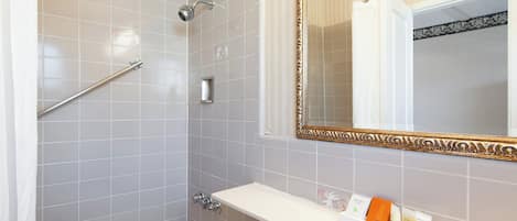 Un baño con ducha, inodoro y lavamanos con artículos de aseo.