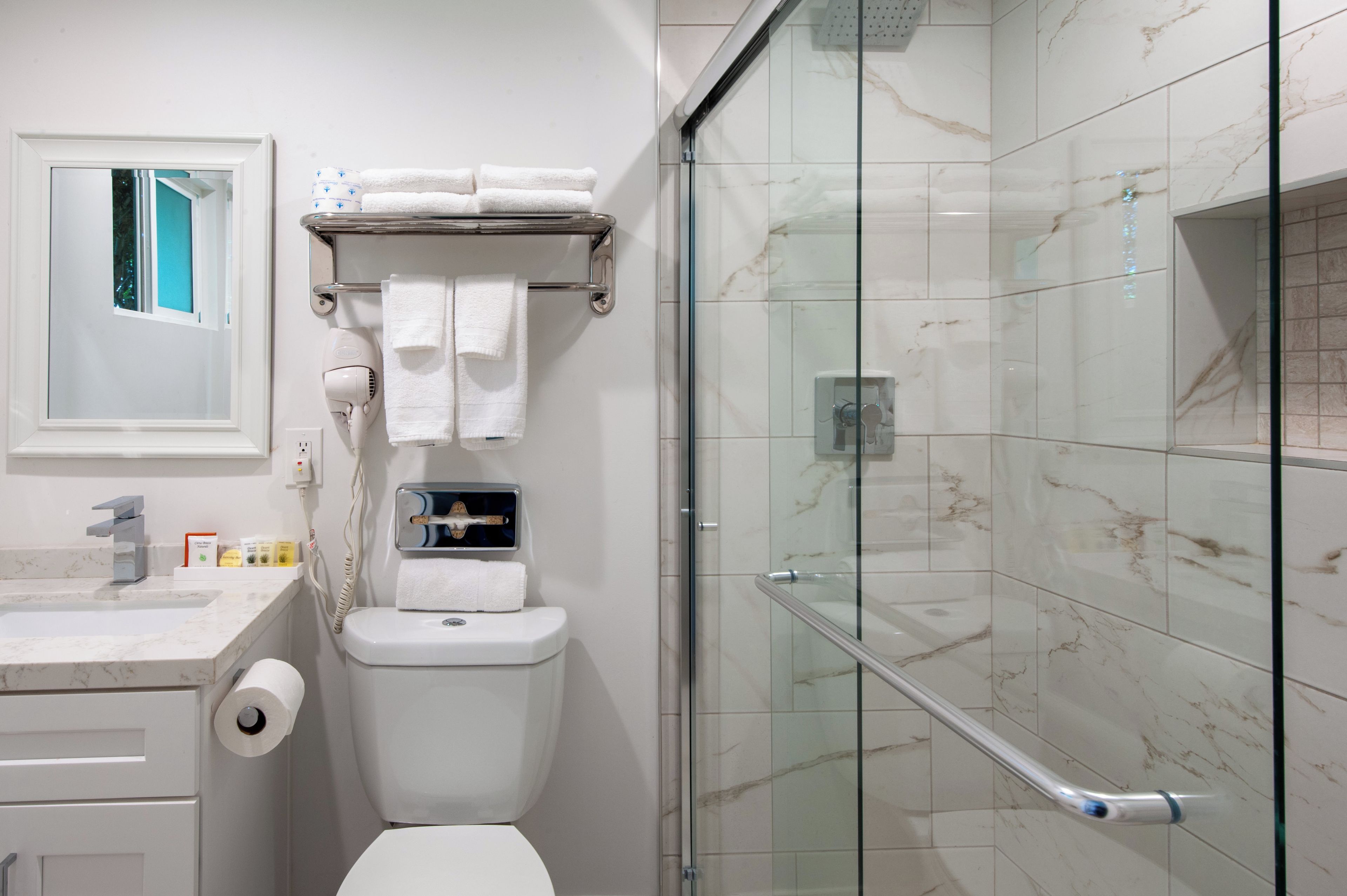 Une salle de bain moderne avec des toilettes, une douche à parois de verre et un mur recouvert de carreaux de marbre.