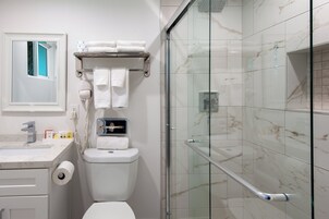 Un baño moderno con inodoro, cabina de ducha de vidrio y pared revestida de mármol.