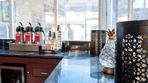 A coffee station with espresso machines and a coffee maker, a decorative glass vase, and a patterned container. - Studio City Court Yard Hotel (Studio City)