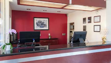 A reception desk with two HP computers, a framed picture on the wall, and a potted plant.