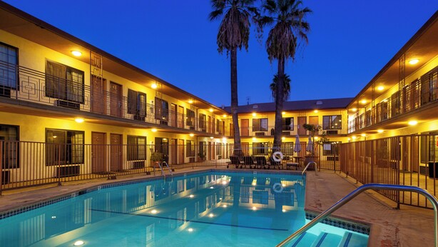 A hotel with a swimming pool, multiple balconies, and palm trees. - Studio City Court Yard Hotel (Studio City)