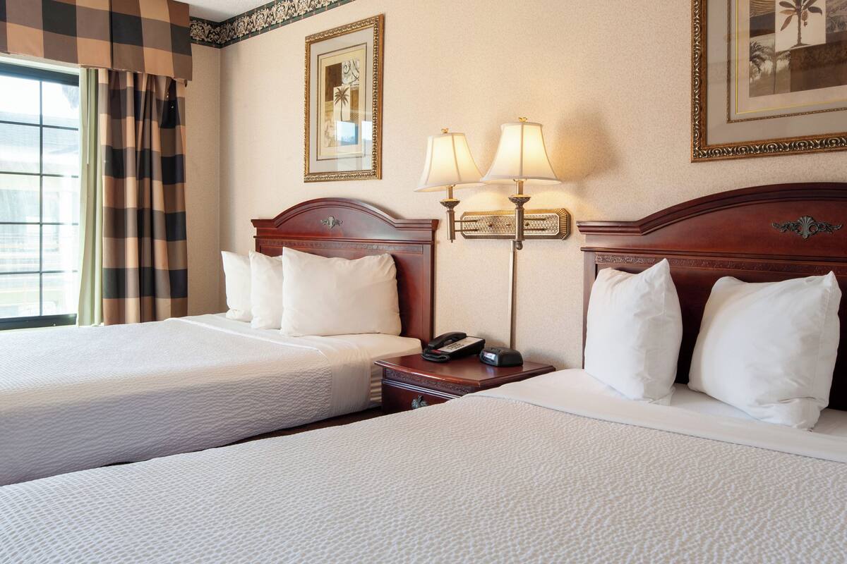 Habitación de hotel con dos camas, una mesita de noche con teléfono y dos lámparas de pared.