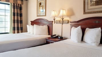 Habitación de hotel con dos camas, una mesita de noche con teléfono y dos lámparas de pared.