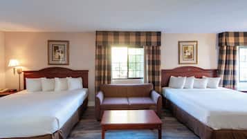 Habitación de hotel con dos camas, un sofá, una mesa de centro de madera y una lámpara.