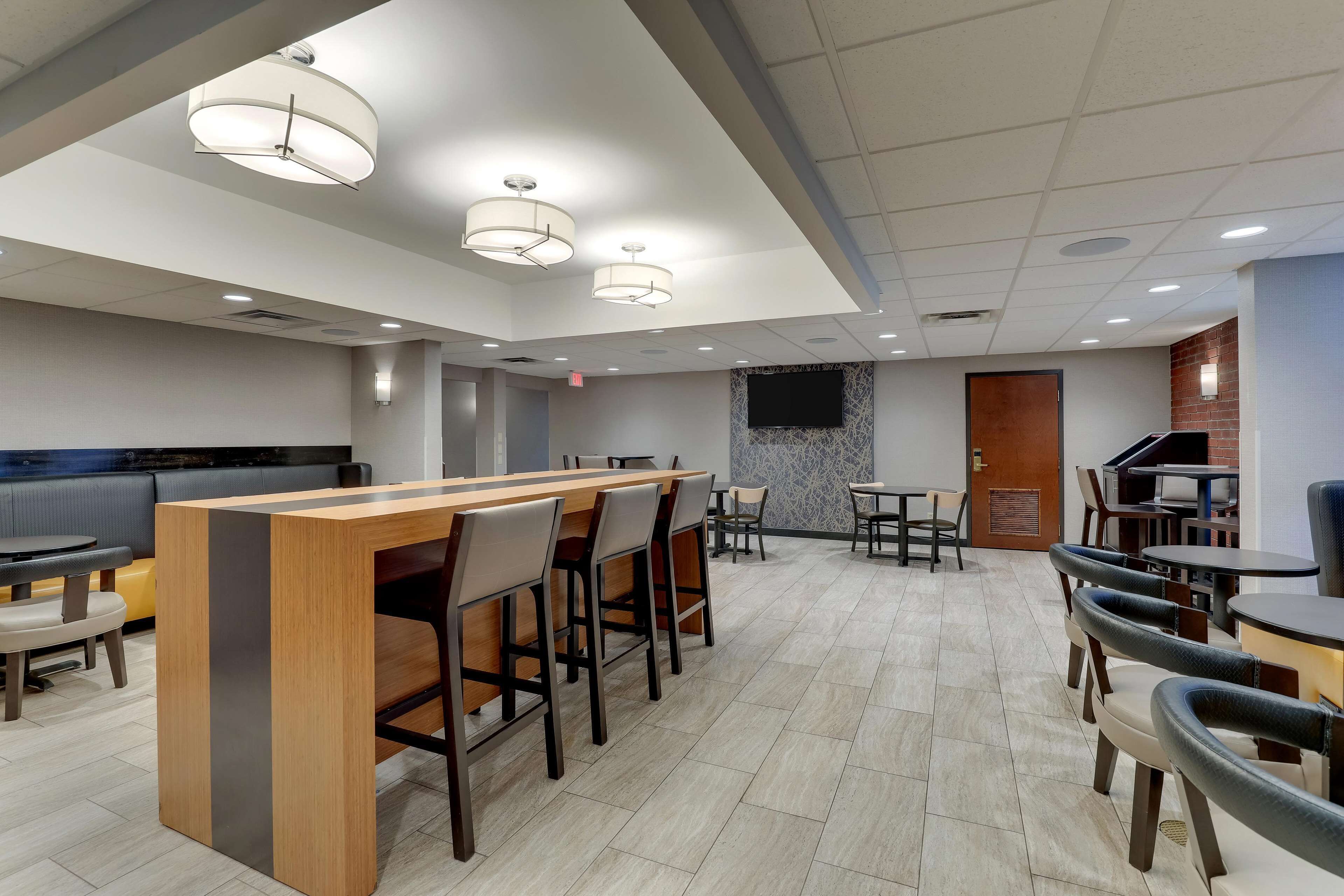A modern restaurant with a bar area, multiple dining tables, and chairs.