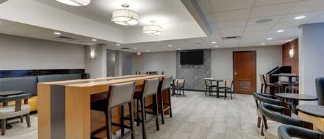A modern restaurant with a bar area, multiple dining tables, and chairs.