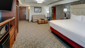 A hotel room with a large bed, a sofa, a television, and a desk with a lamp. - Drury Inn Paducah (Paducah)