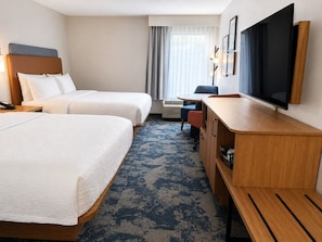 Une chambre d’hôtel avec deux lits, un bureau, une télévision et une fenêtre avec des rideaux.