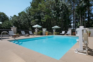 A swimming pool with lounge chairs and umbrellas, surrounded by trees. - Hampton Inn Cartersville (Cartersville)