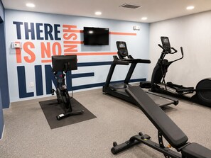 Una palestra con attrezzature per esercizi, tra cui tapis roulant, ellittica e cyclette.