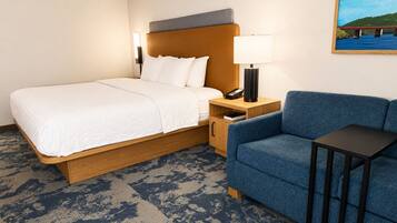 Een hotelkamer met een bed, een blauwe bank, een nachtkastje met een lamp en een schilderij aan de muur.