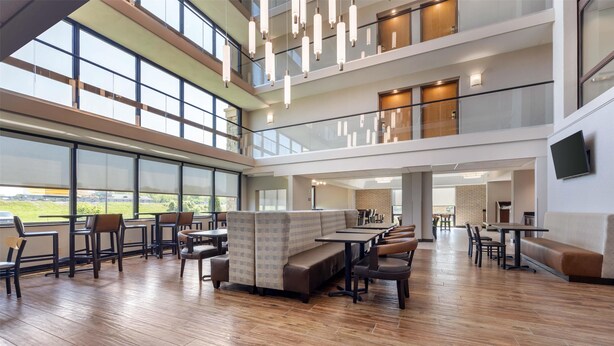 A spacious indoor area with multiple seating arrangements, including benches and tables, and large windows offering views of the outdoors.