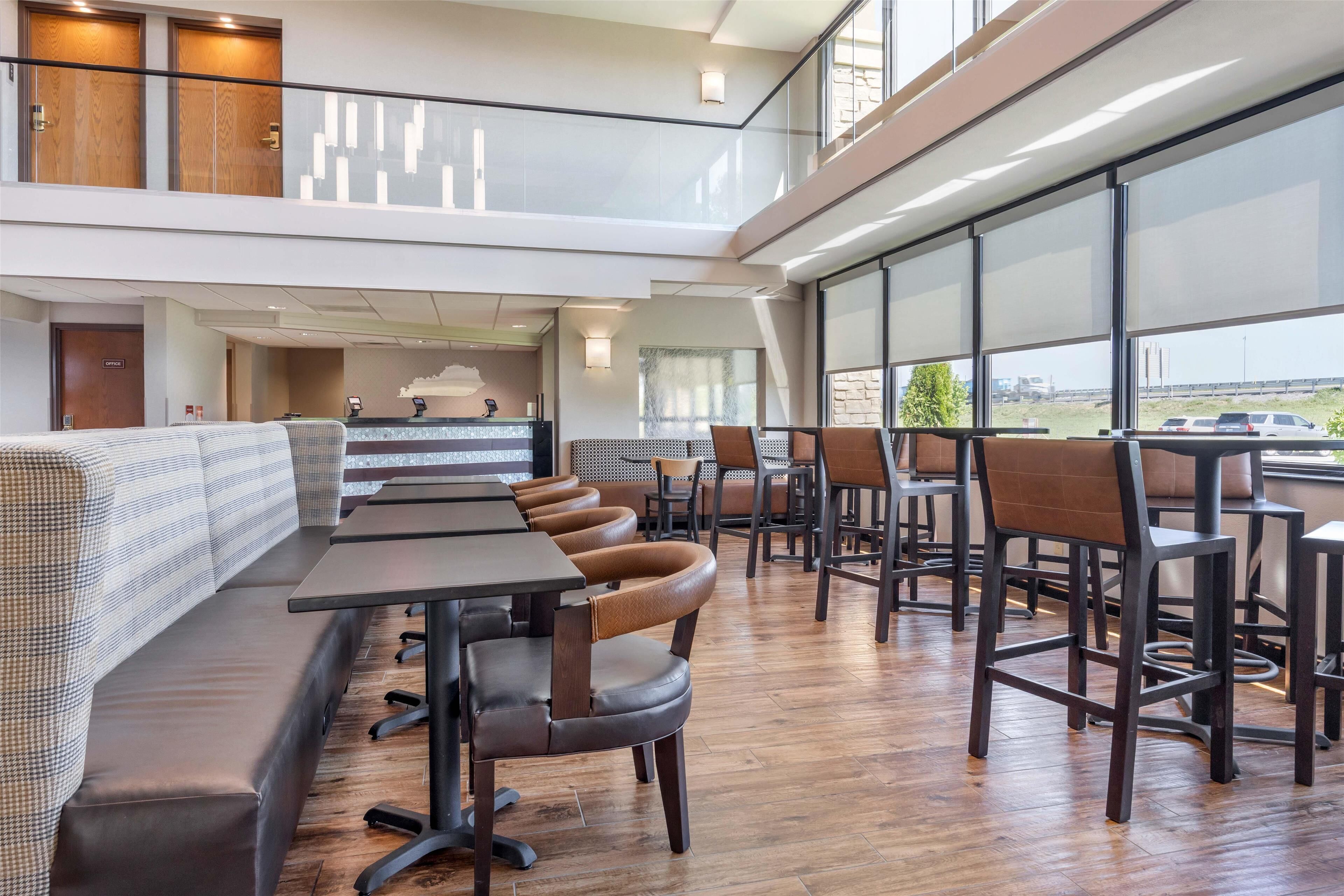 Un restaurante moderno con techo alto, suelo de madera y una zona de estar con mesas y sillas.