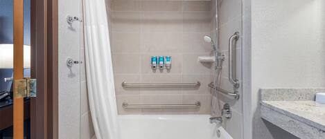 Une salle de bain moderne équipée d’une baignoire, d’une douche et de barres d’appui.
