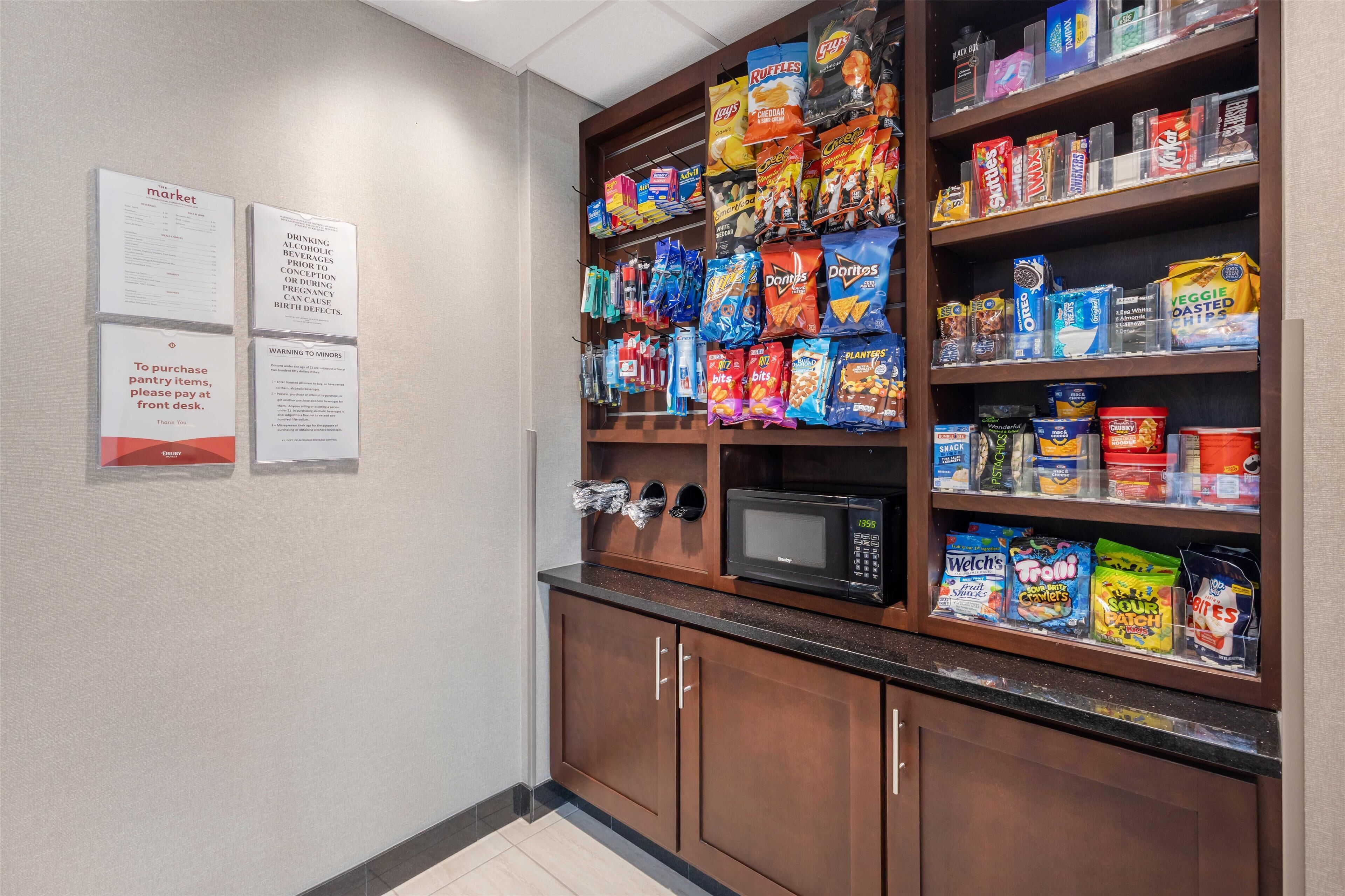 A pantry stocked with snacks and a microwave.