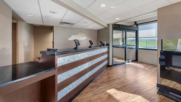 A reception area with a counter, glass doors, and a view of the outdoors.