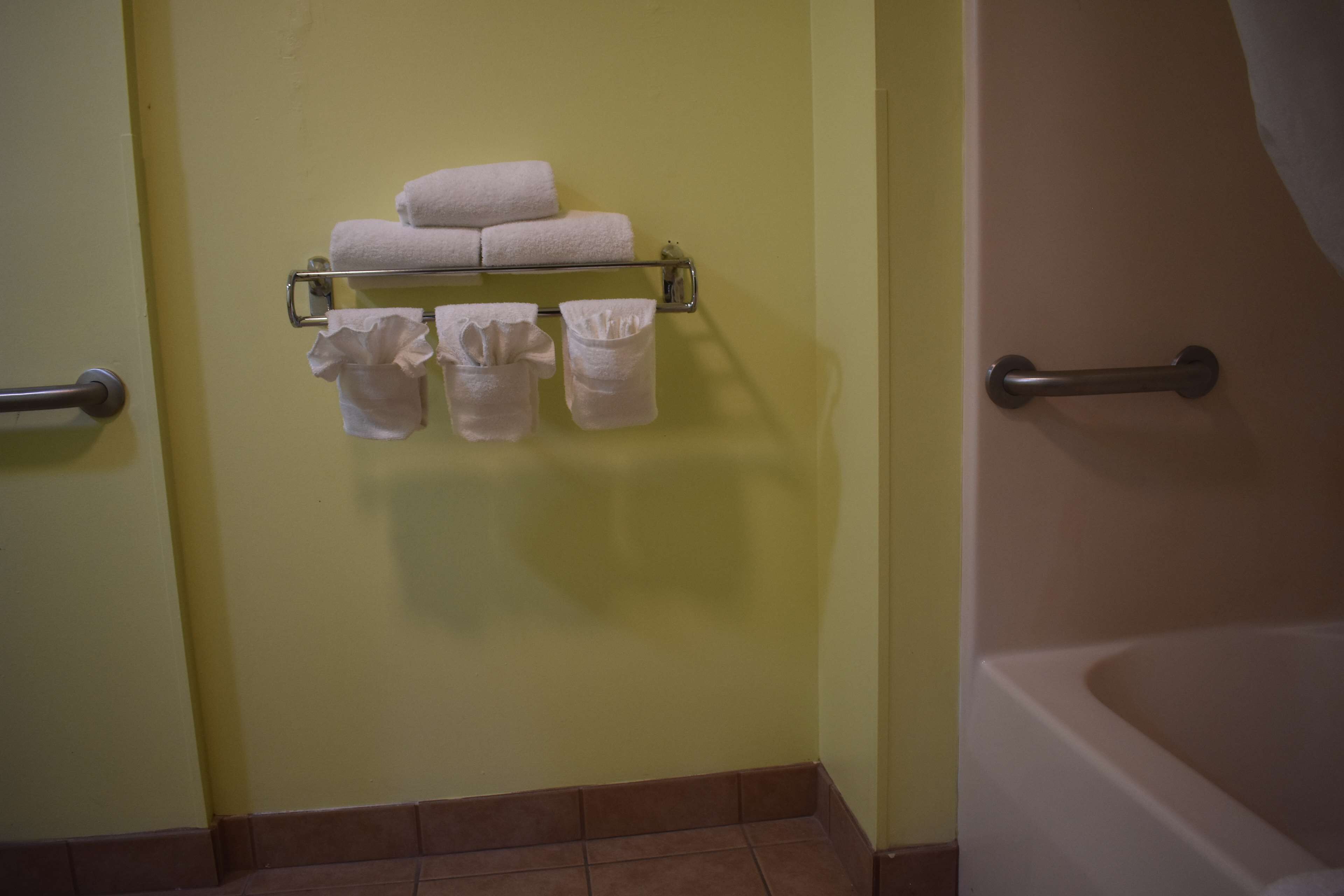 Une salle de bain équipée d’un porte-serviettes où sont pliés les serviettes, ainsi que d’un sèche-mains.