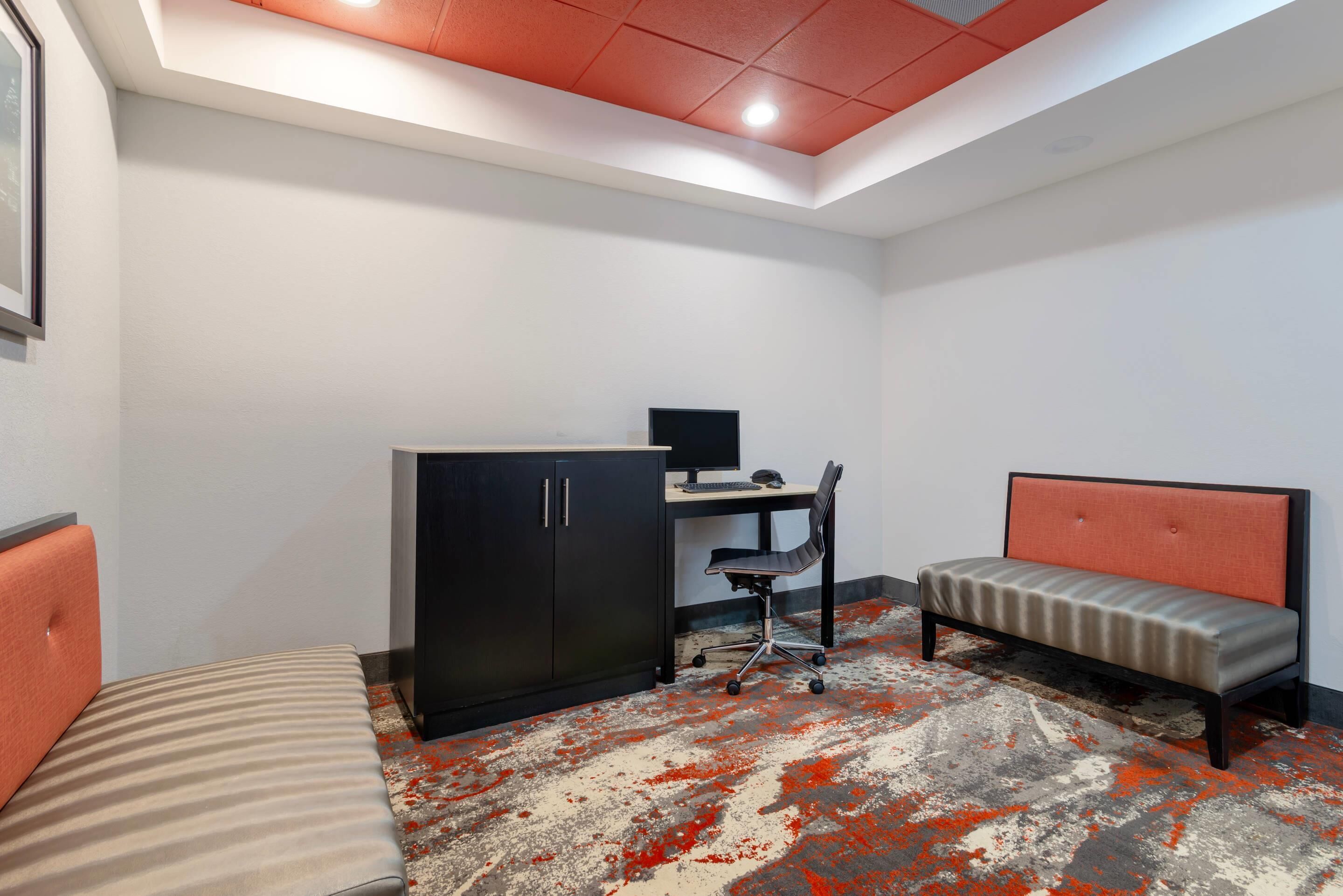 A room with a bed, a desk with a computer, and a chair.