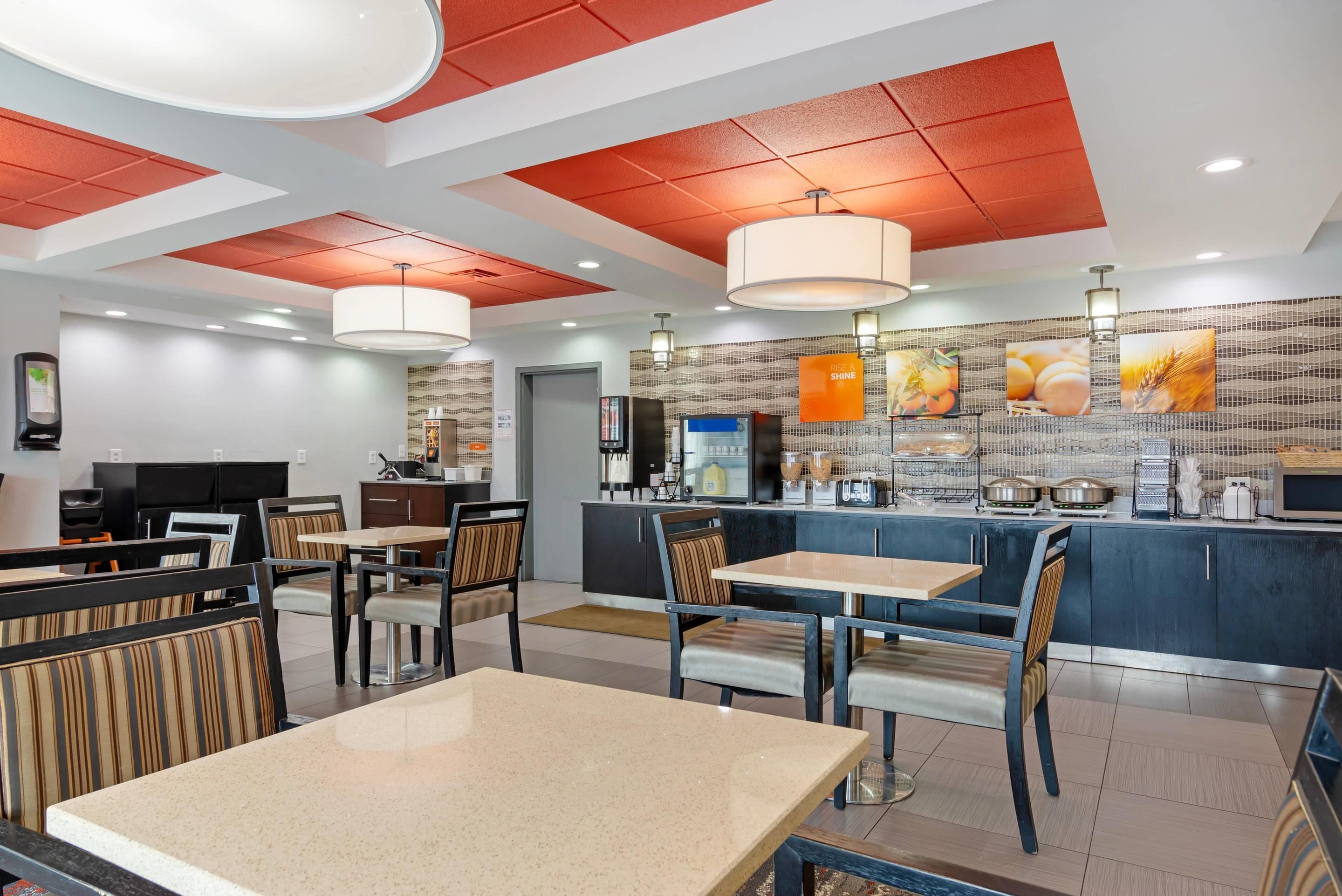 A modern restaurant with high ceilings, red paneling, and a variety of seating options including tables and booths.