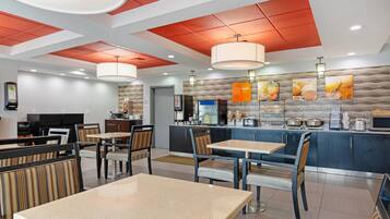 A modern restaurant with high ceilings, red paneling, and a variety of seating options including tables and booths.
