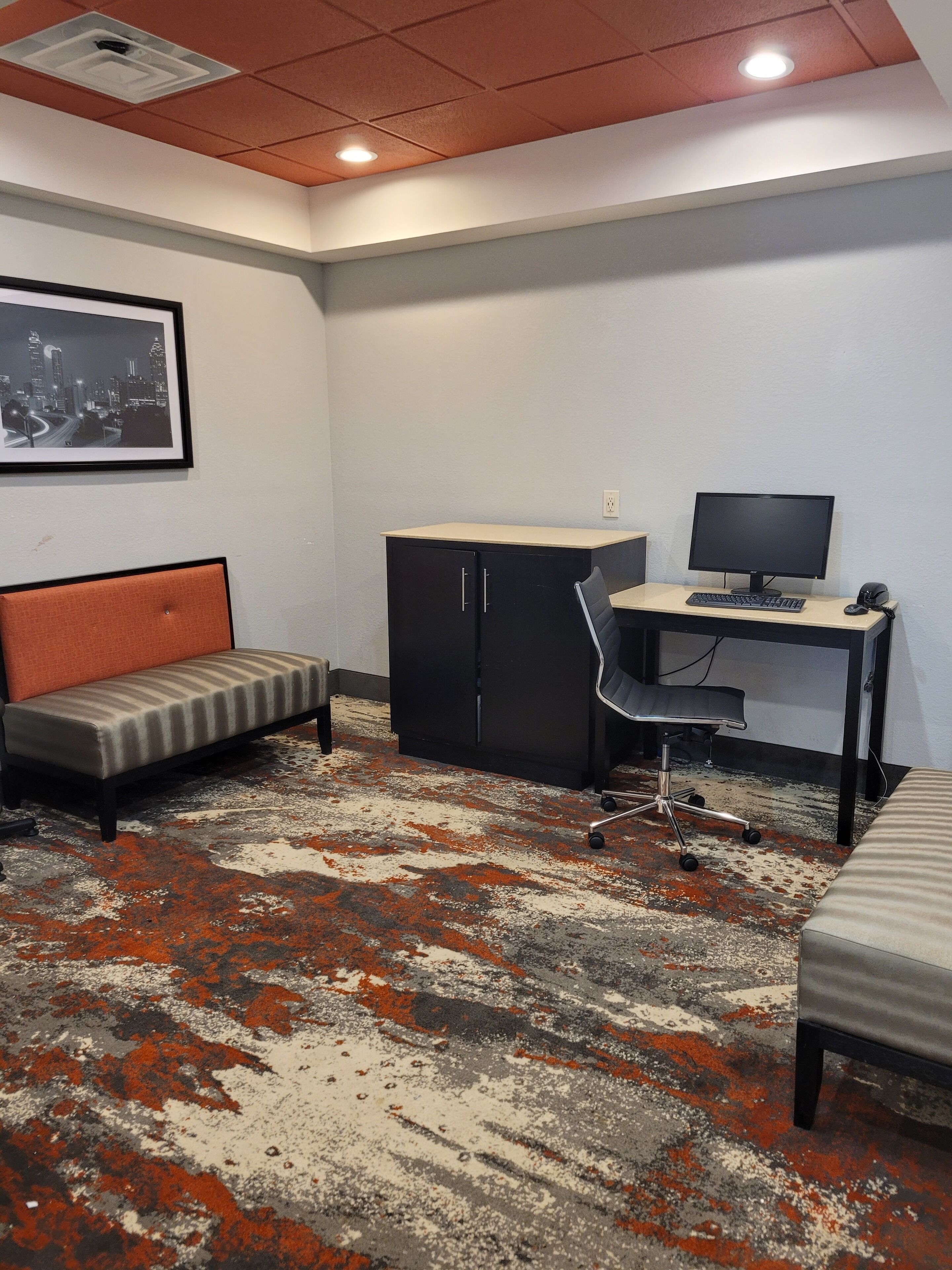 A room with a desk, computer, and a cushioned bench.