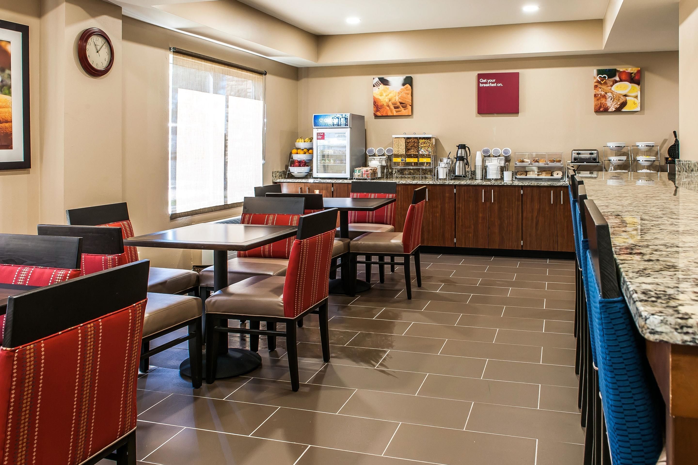 A restaurant with booths and tables, a refrigerator, and a coffee station.
