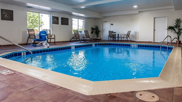 Une piscine intérieure à l’eau claire, avec un échelle et des chaises longues.