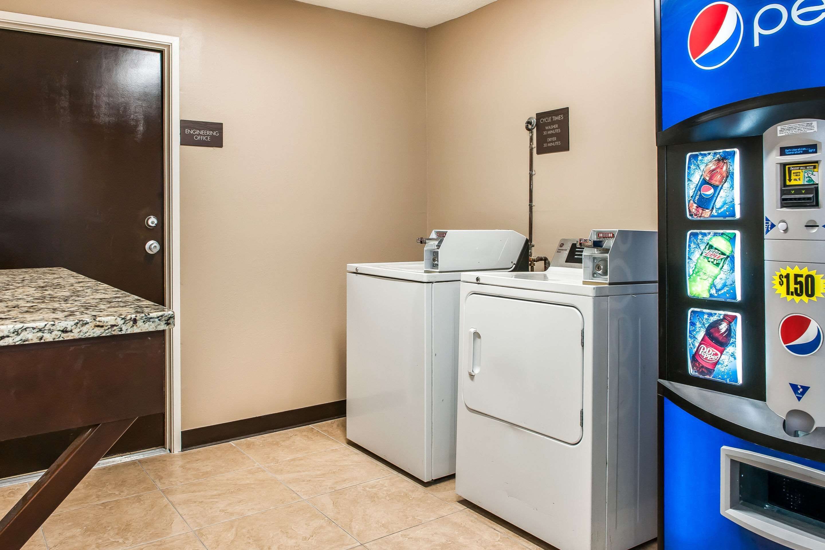 A laundry area with a washing machine, dryer, and a Pepsi vending machine.