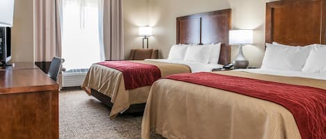 Una habitación de hotel con dos camas, un escritorio, un televisor y una lámpara.