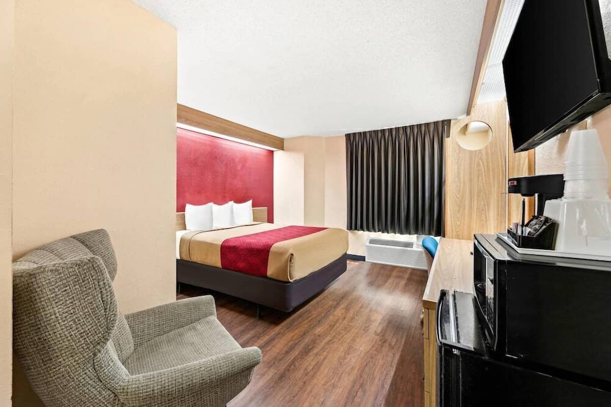 Une chambre d’hôtel équipée d’un lit, d’une chaise, d’un bureau avec un ordinateur et d’une télévision.