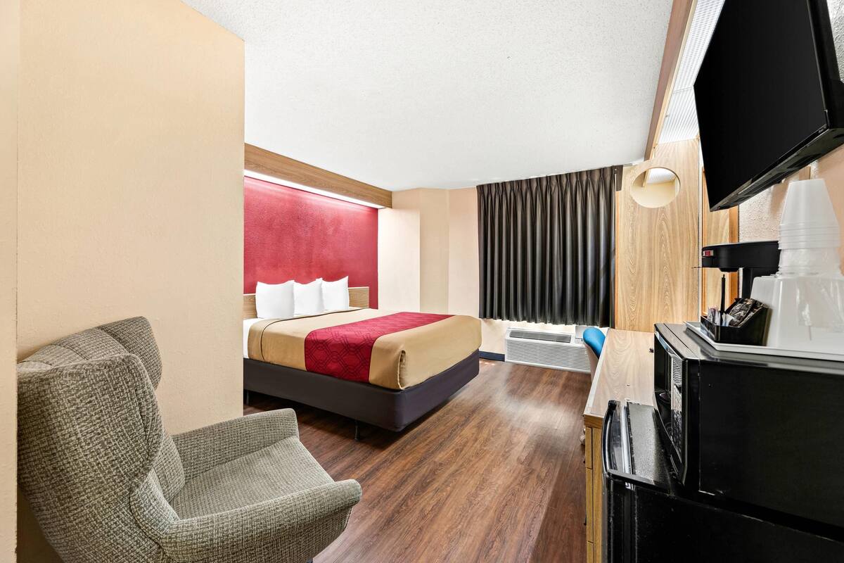 Une chambre d’hôtel équipée d’un lit, d’une chaise, d’un bureau, d’une télévision et d’une machine à café.