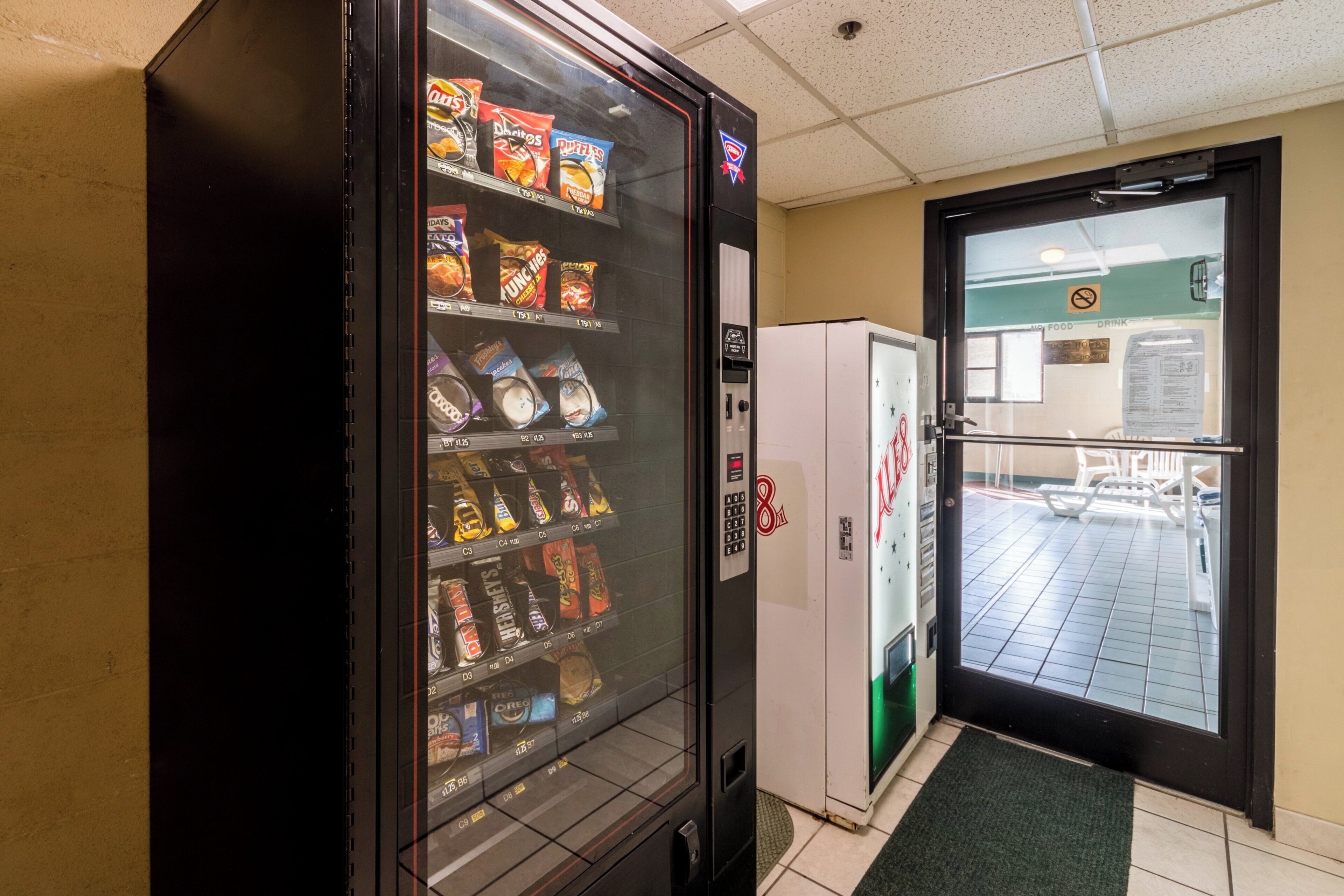 A vending machine with snacks and a refrigerator in a hallway.