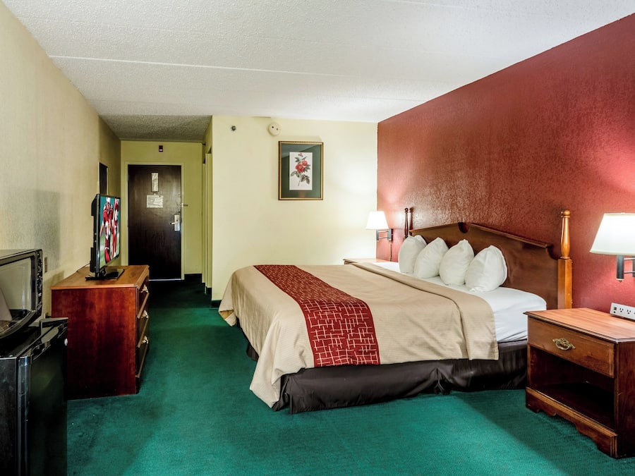 Una camera d'albergo con un letto, lampade sui comodini, una televisione e un comò.