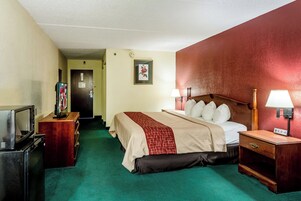 Habitación de hotel con cama, lámparas de noche, televisión y cómoda.