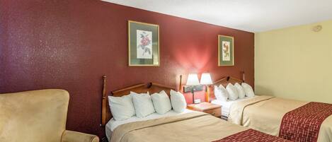 A hotel room with two beds, a chair, and a nightstand with lamps.