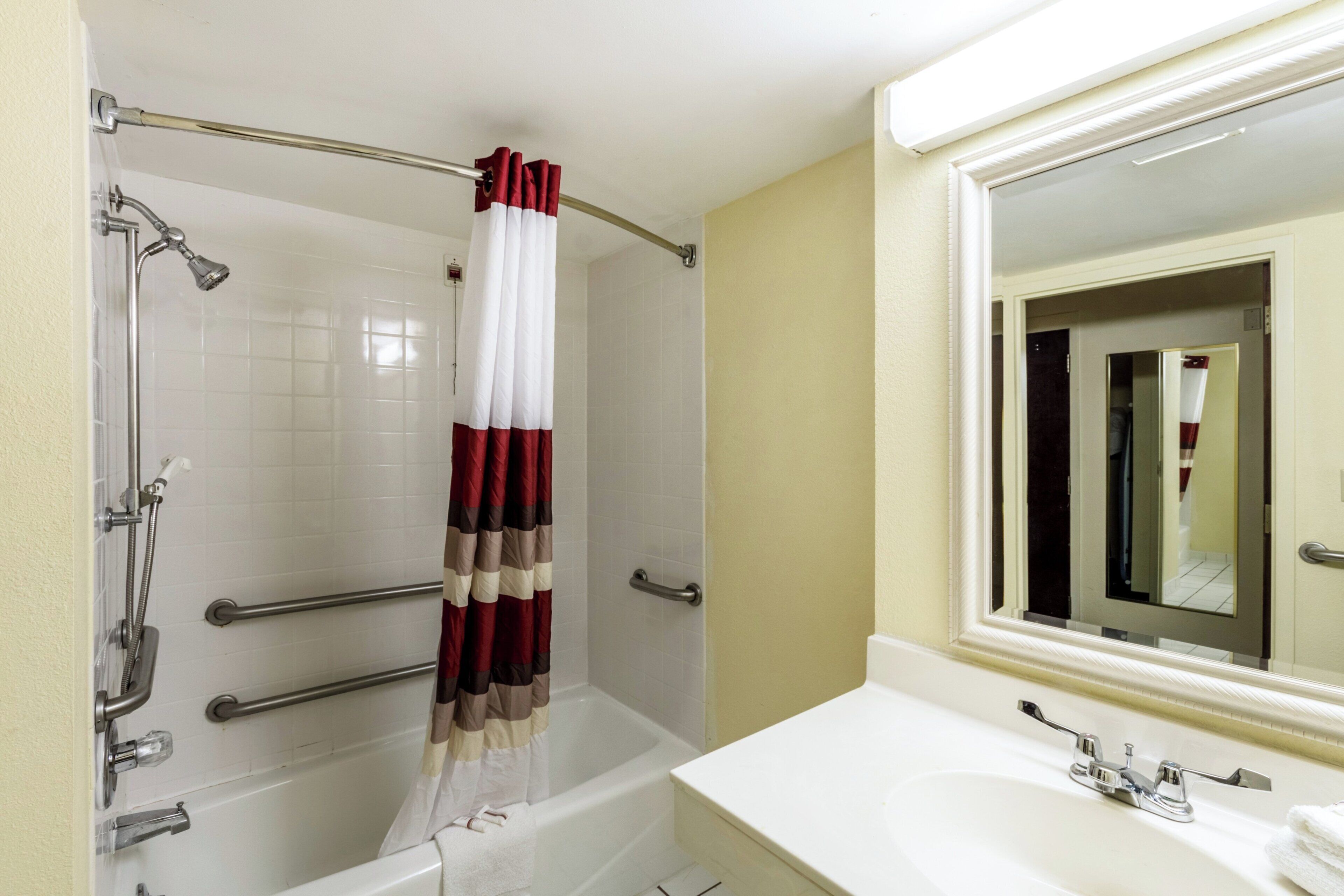 Un baño con bañera, ducha, lavamanos y espejo.