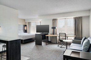 A modern hotel room with a bed, desk, TV, sofa, and a small table. - Residence Inn By Marriott Merrillville (Merrillville)
