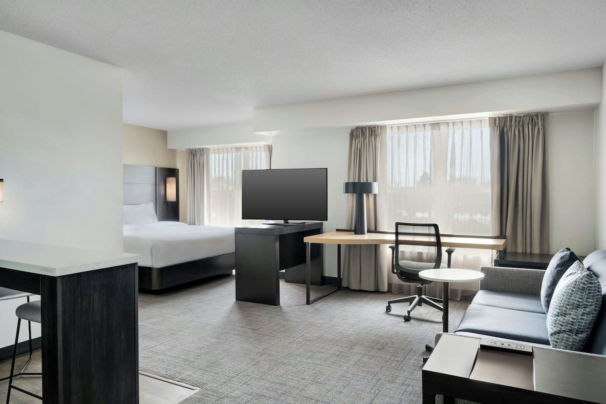 Een hotelkamer met een bed, bureau, televisie, bank en een kleintje tafel.