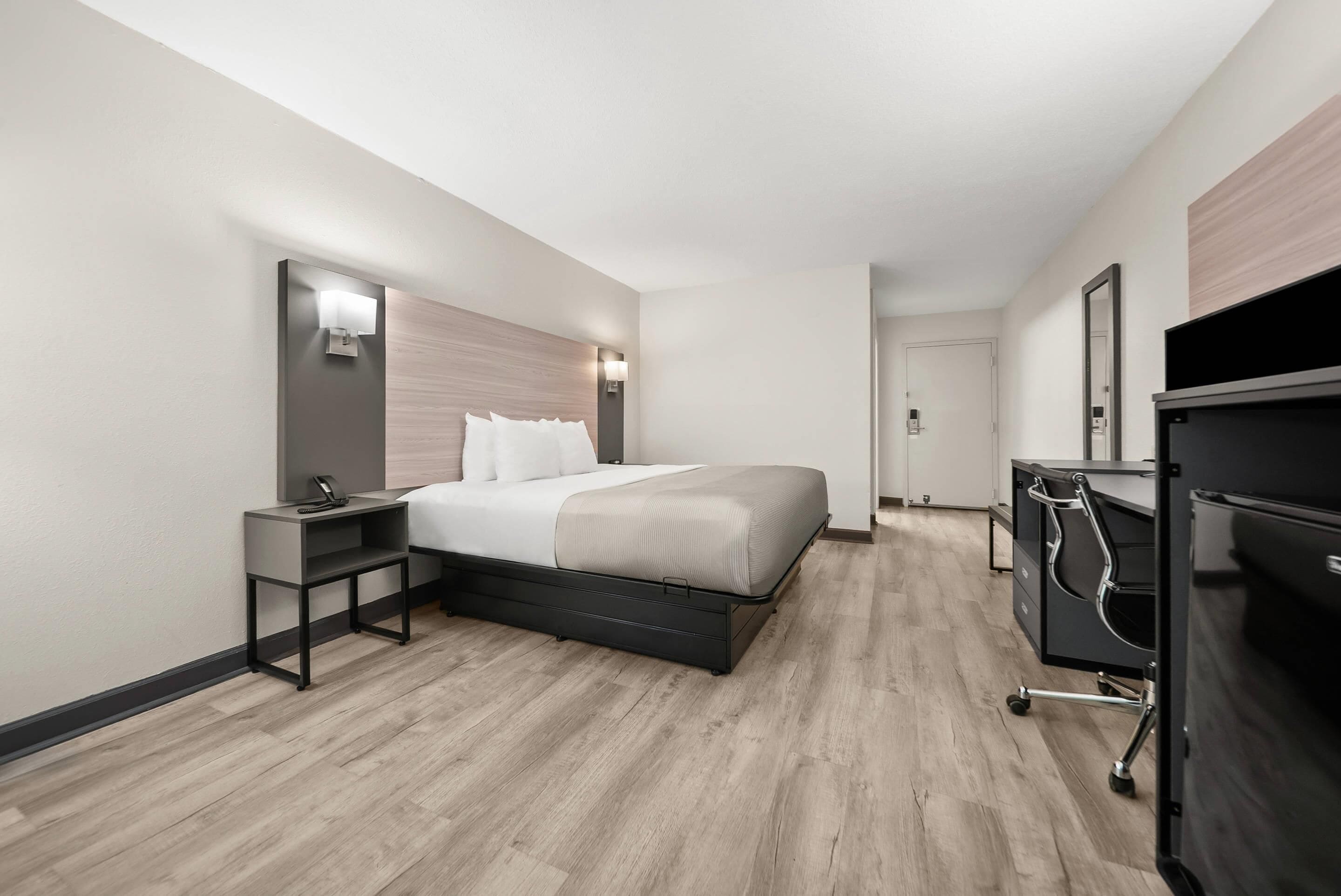 Une chambre d’hôtel moderne, dotée d’un grand lit, de tables de chevet, d’un bureau et d’une armoire.