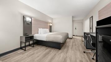 Une chambre d’hôtel moderne, dotée d’un grand lit, de tables de chevet, d’un bureau et d’une armoire.