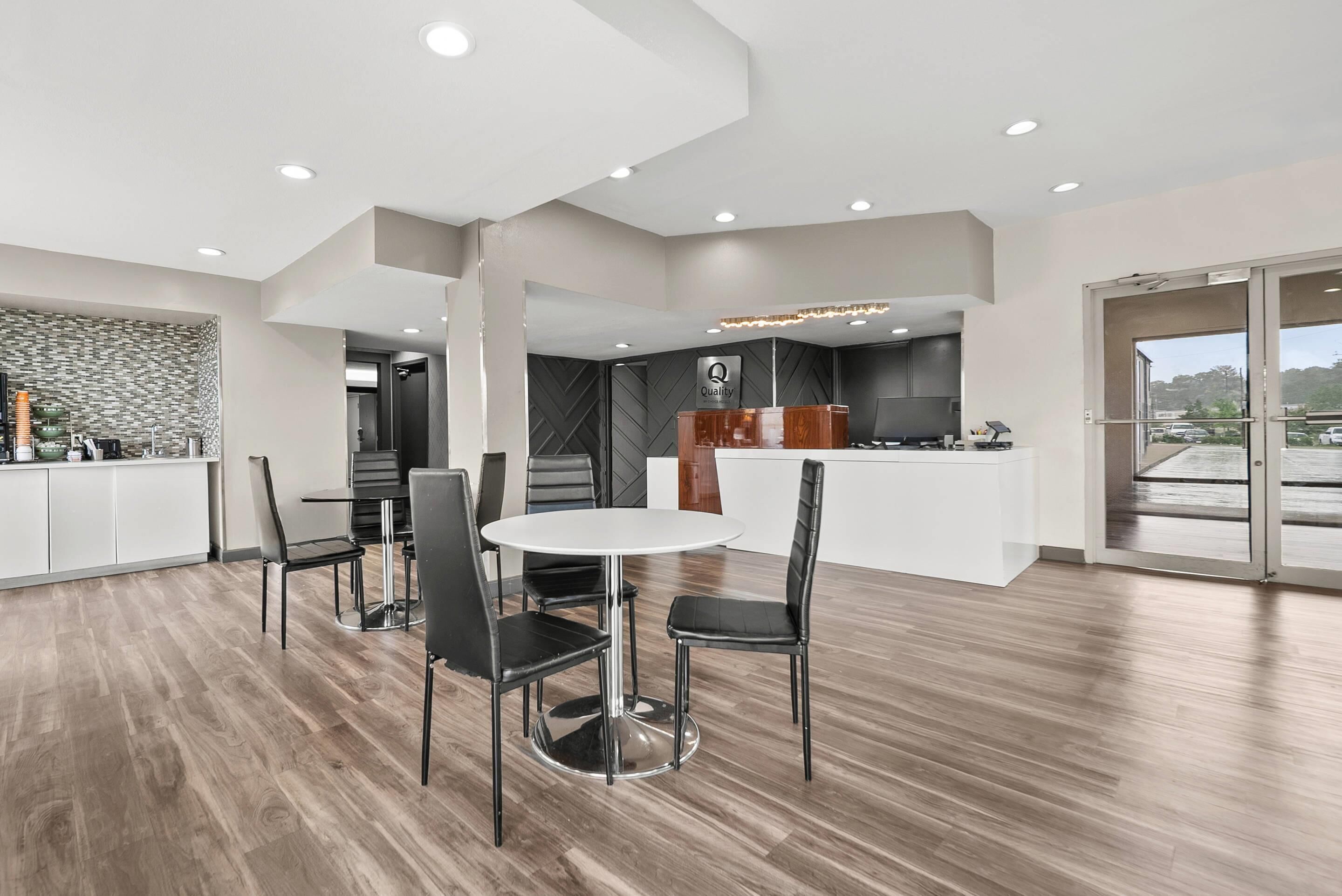 Une cuisine moderne dotée d’un îlot central, d’un coin repas avec une table ronde et des chaises, et d’une grande fenêtre offrant une vue sur l’extérieur.