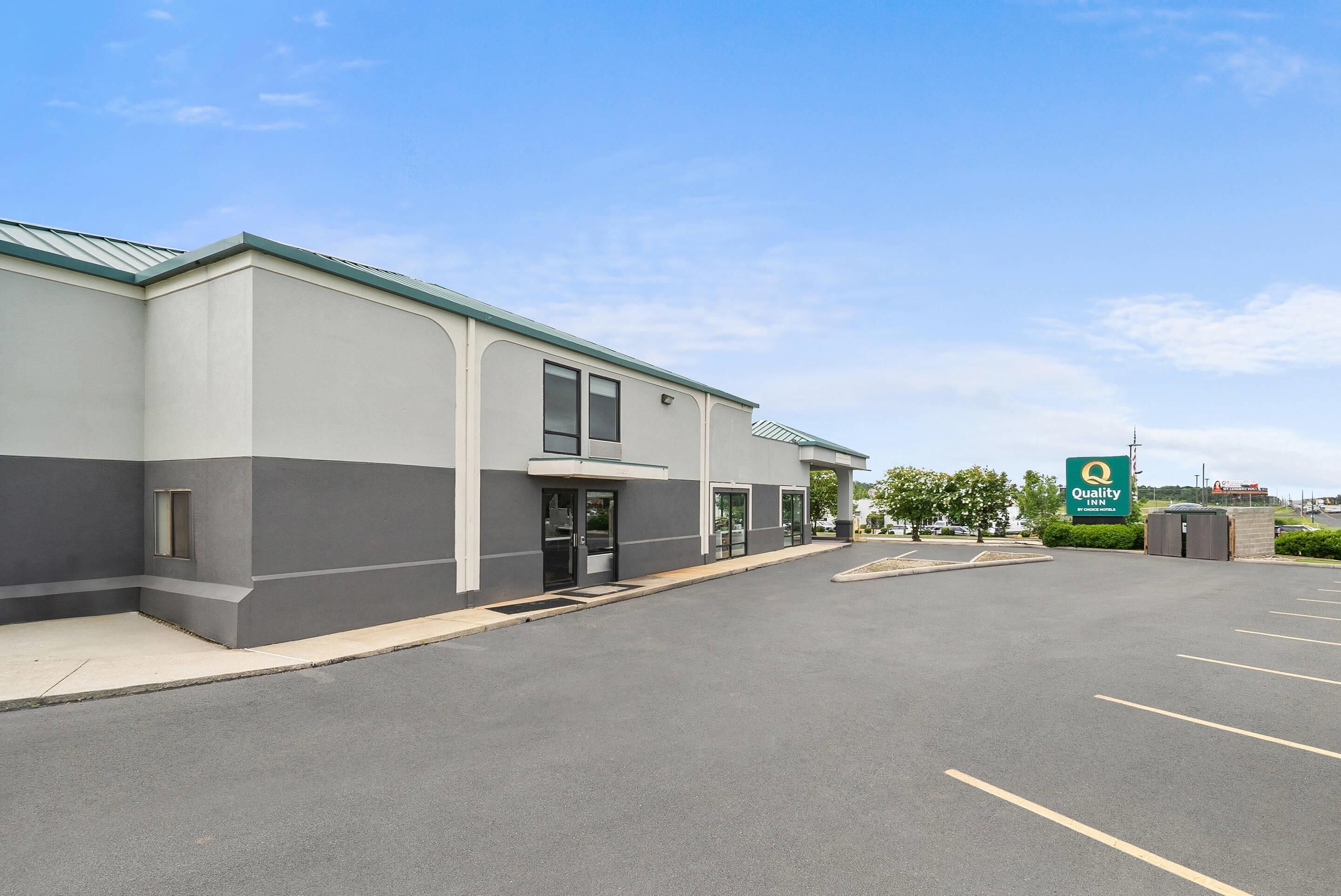 A modern building with a parking lot, a green sign, and a clear sky.