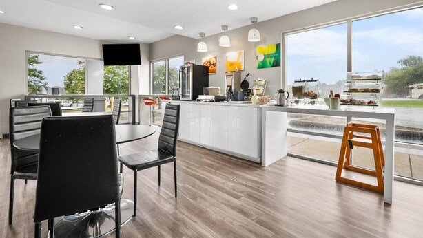 A modern kitchen with a large island, dining area with chairs, and a view of the outdoors. - Quality Inn Auburn Campus Area I-85 (Auburn)