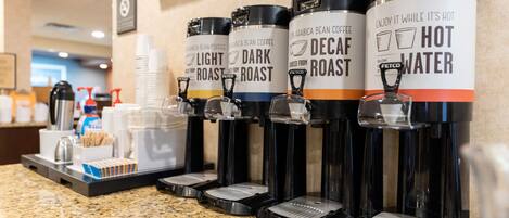 Estación de café con dispensadores etiquetados como 'Tueste Suave', 'Tueste Oscuro', 'Tueste Descafeinado' y 'Agua Caliente'.