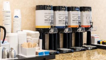 A coffee station with multiple dispensers labeled "100% Arabica Bean" and "Sourced from Central America & South America."
