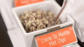 Un bar de aperitivos con recipientes etiquetados, que incluyen un cartel que dice 'Crème De Menthe Mint Chips'.
